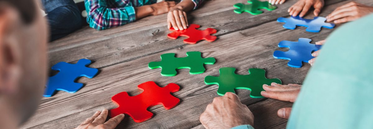 Business people and puzzle on wooden table, teamwork concept